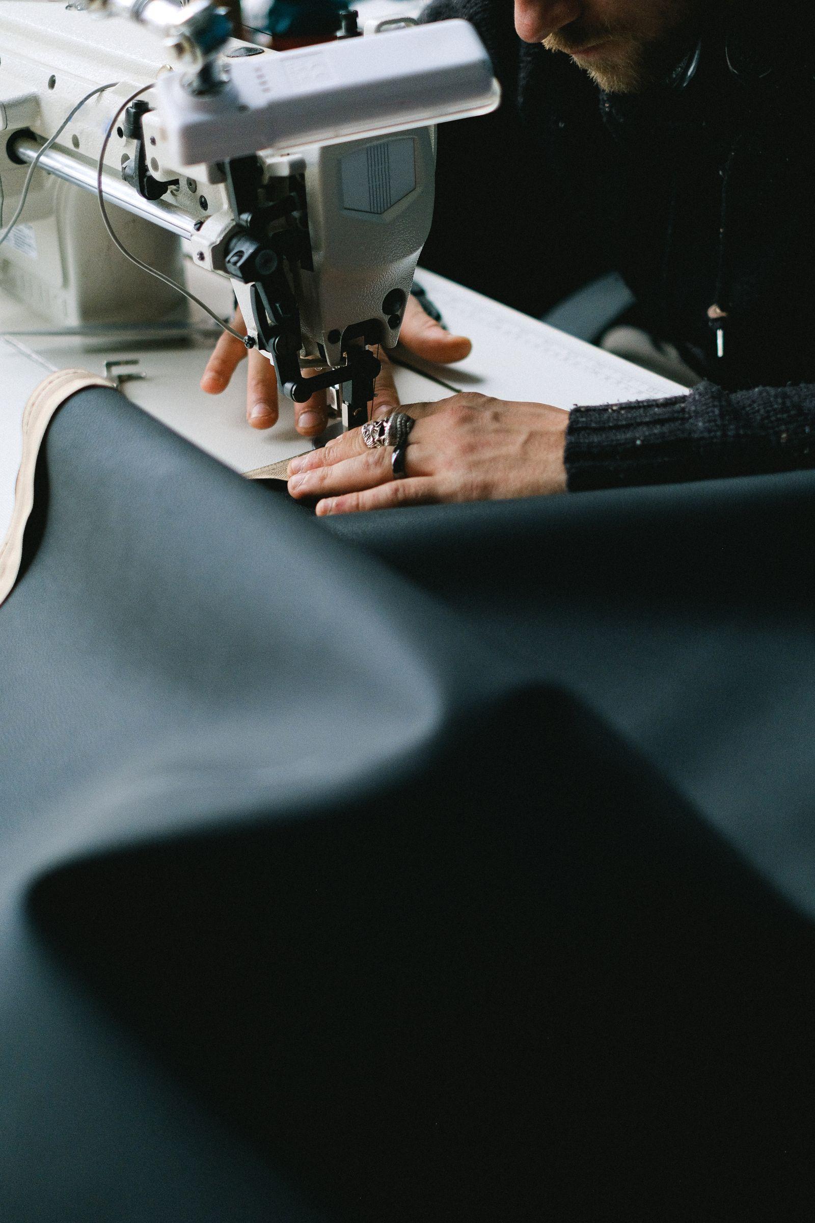 A pair of hands guiding fabric through a sewing machine