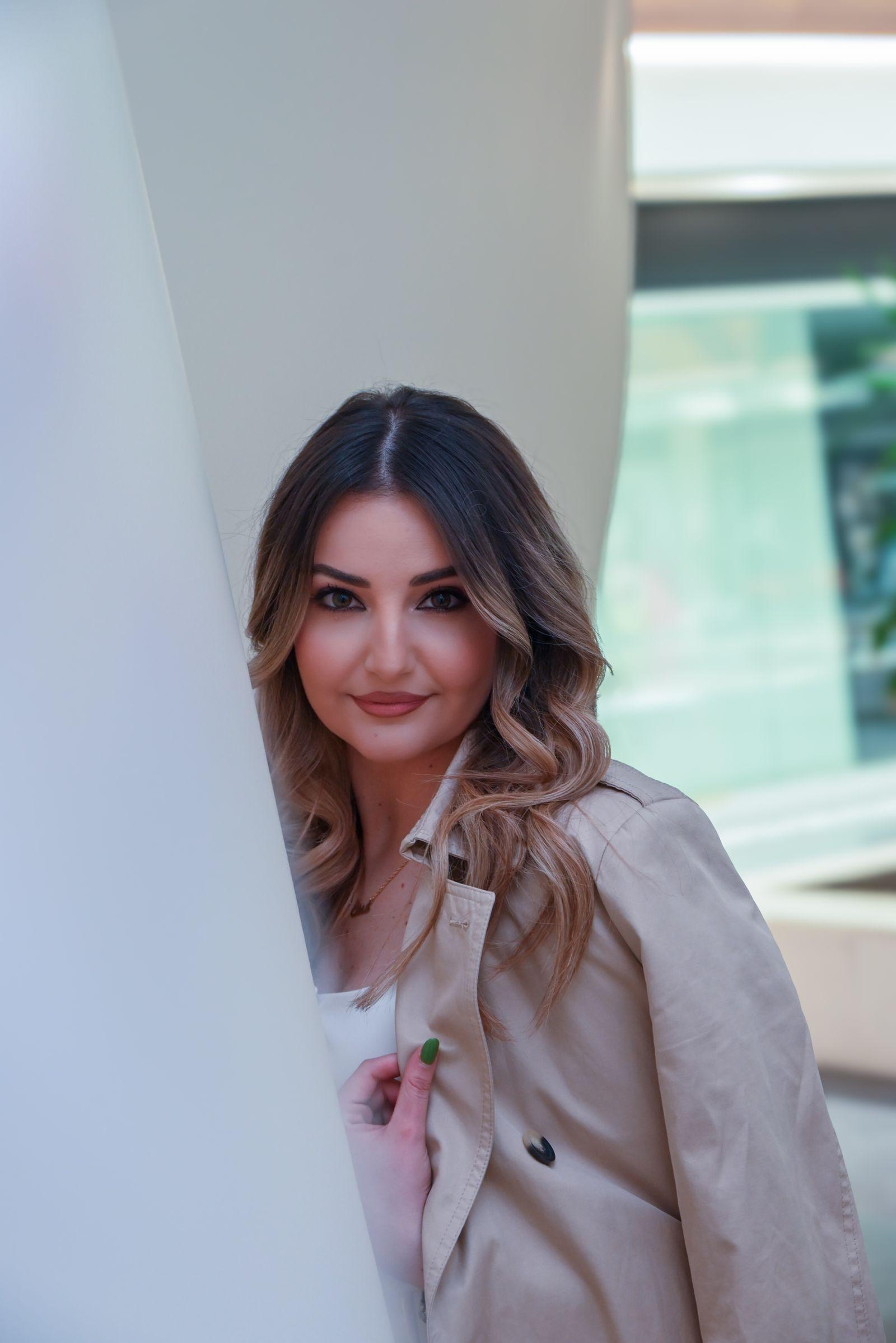 A trench coat worn outdoors against a modern building